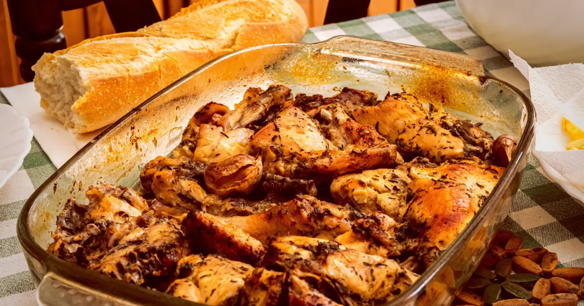 A freshly baked leftover chicken casseroles with a golden, cheesy topping served in a white baking dish, surrounded by fresh herbs and ingredients.